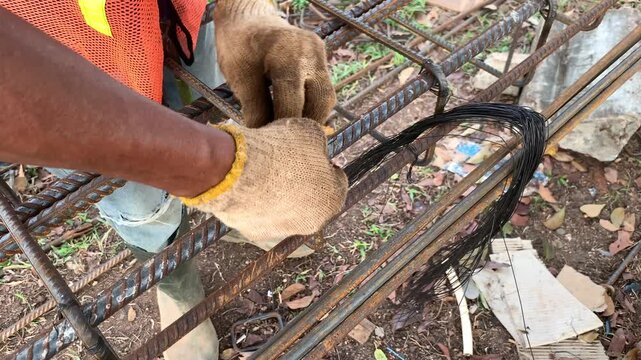 Hands of construction worker that holding a plier to cutting a wire. Making series of iron for foundation and column building. Connect irons for frame pillar. Civil work. Building structure work