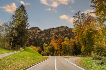 Fototapeta premium The winding road to Schwaegalp in the Swiss Alps leads through a vibrant autumn landscape in the canton of Appenzell Ausserrhoden, Switzerland