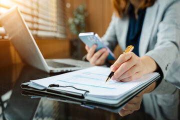 Hands of woman using mobile phone in modern office with laptop and digital tablet at office