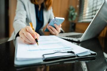 Hands of woman using mobile phone in modern office with laptop and digital tablet at office