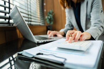 Businesswoman hand working with finances about cost and calculator and laptop with tablet on withe...