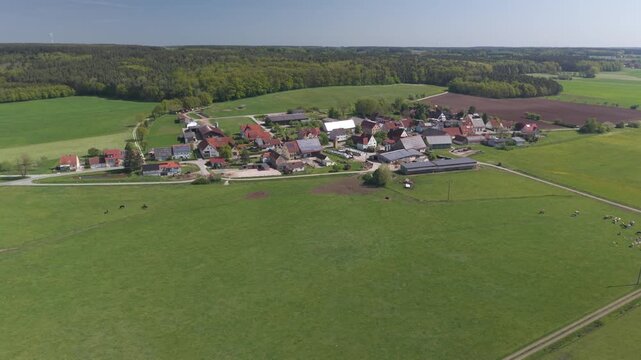 A drone fly over during Spring across a small Franconia village called Thann nearby Ansbach embedded in green landscape and and a small river