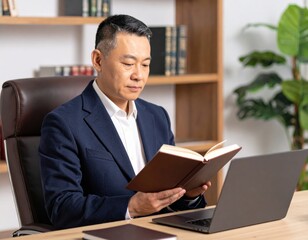 Obraz premium デスクで読書とパソコン作業をするシニア男性