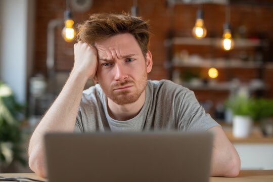 Frustrated Young Man Facing Equipment Breakdown at Home: Struggling with Slow Internet and Annoying Gadgets