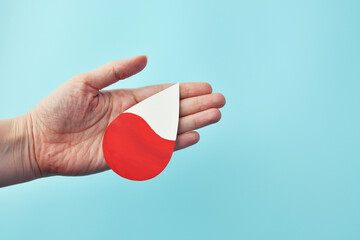 Hand holding a blood drop symbol for blood donation and medical concepts