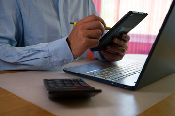 Businessman using smartphone and laptop in office. Man scrolls social media, checks email, manages...