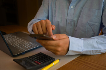 Businessman using smartphone and laptop in office. Man scrolls social media, checks email, manages...