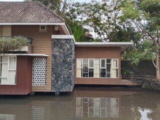A building built over a pond. The reflection of buildings on the water creates a striking visual...