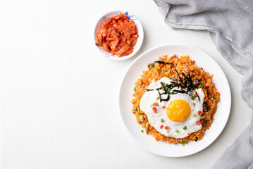 Top view of Korean kimchi fried rice with fried egg, pork, sesame seed, chili, spring onion and seaweed