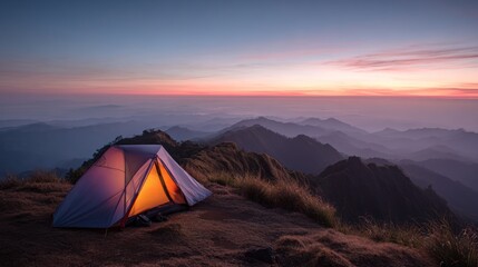 Mountaintop campsite at sunrise.  A small tent glows warmly on a high mountain peak overlooking a vast landscape of misty hills and a vibrant sunrise