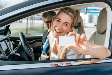 Excited young woman shows her new driving license after passing her test successfully