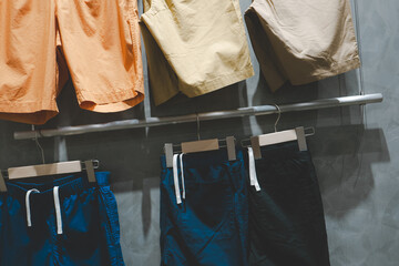 Colorful Casual Shorts Displayed on Hangers in Clothing Store. A stylish clothing store display featuring casual shorts in various colors hanging on modern wooden hangers.