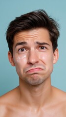 Obraz premium European Man with Makeup Stains Looking Disappointed Against a Teal Background
