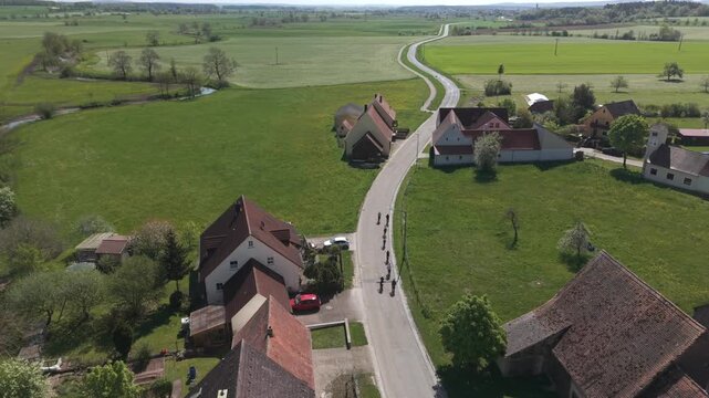 A drone fly over during Spring across a small Franconia village called Thann nearby Ansbach embedded in green landscape and and a small river
