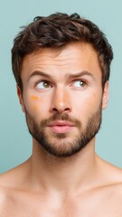 Fototapeta premium European Man With Makeup Stains on His Face Looking Thoughtfully Against a Soft Green Background