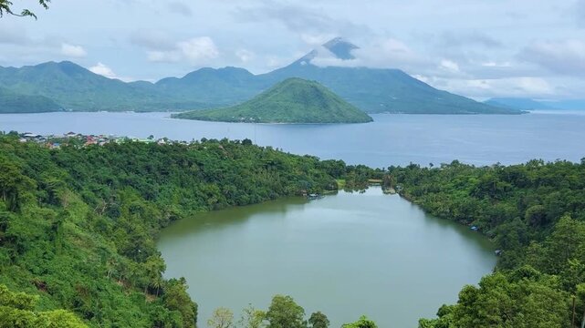 Ngade Lake, Ternate, North Mollucas, Indonesia. Beautiful green lake with two mountains and ocean in the background