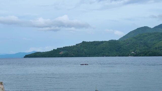A boat sailing in middle sunny day with beautiful mountain in the background. Tidore Island, North Mollucas, Indonesia