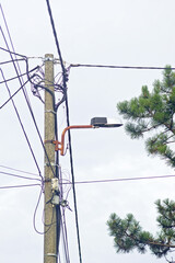 Electric pole with power lines and with street lamp, vertical photo. Concept of electrification,...