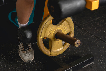 An anonymous man prepares to do a set of leg extensions while at the gym. Training and strengthening quads using plate loaded gym machine equipment.