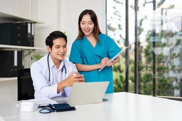 Doctor and nurse discussing over a medical report in hospital. Asian doctor and nurse checking...