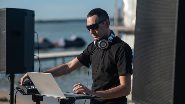 Caucasian man works as a DJ on the beach. 