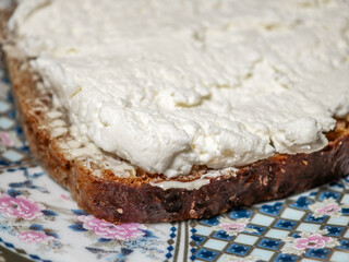 A close-up of a slice of brown bread with butter and cream cheese