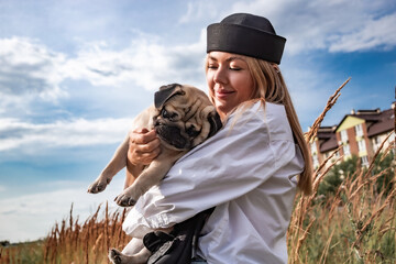 Young happy beautiful woman holding and hugging her beloved dog during a walk with harness and...