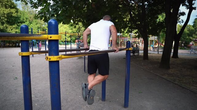 Man with glucose monitoring sensor doing push-ups on parallel bars
