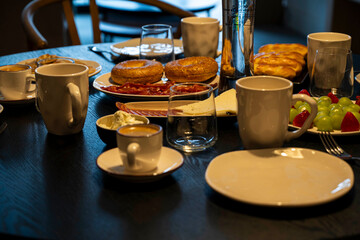 A table with a variety of food and drinks, including a bottle of beer. The table is set for a meal, with plates, cups, and utensils. Scene is casual and inviting