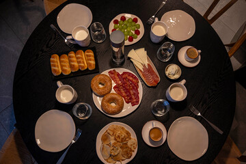 A table with a variety of food and drinks, including a plate of bagels and a bottle of water