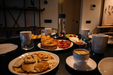 A table with a variety of food and drinks, including a plate of bagels and a bottle of water