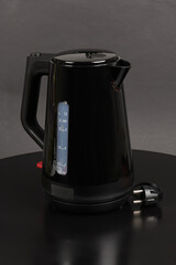 A black electric kettle on a black background.