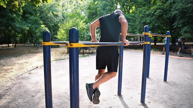 Man with glucose monitoring sensor doing push-ups on parallel bars
