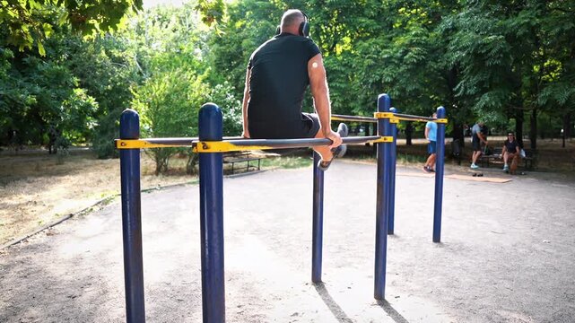 Man with glucose monitoring sensor doing push-ups on parallel bars
