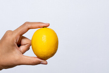 Bright Yellow Lemon Held in Hand on Plain Background