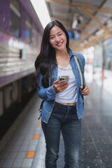 Young woman using smartphone while waiting for train