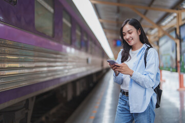 Young woman using smartphone while waiting for train at station