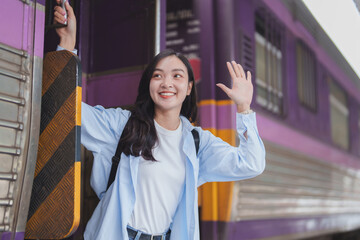 Young woman waving goodbye while boarding train
