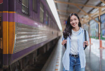 Young woman smiling at train station with backpack ready for travel