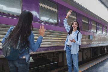Two young tourists waving goodbye at train station