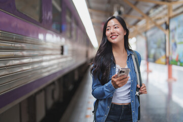 Tourist using smartphone while waiting for train at station