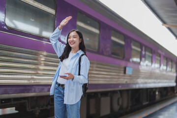 Young woman waving goodbye at train station platform