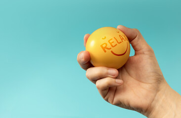 Hand holding Stress ball labeled Relax used for emotional control and mental health practice, helping reduce tension and improve mood