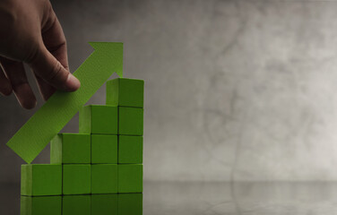 Hand placing green Up arrow on stacked cube bars. financial growth, rising profits, successful investment, and business recovery