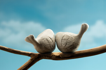 Couple cement bird Side by side on tree branch in sky, symbolizing love, care, and emotional bonding in nature