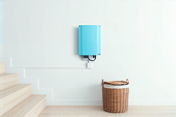 Solar inverter on a wall. A modern, blue solar power inverter or small battery unit mounted on a white wall in a minimalist home interior.