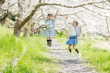 桜並木の下ででジャンプする小学生　