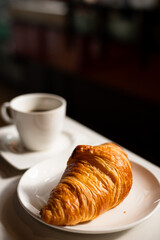 Croissant and coffee on a white table