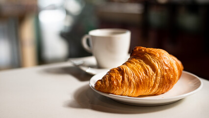 Croissant and coffee on a white table