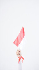A woman hand with red and white Indonesia flag color attribute holding mini Indonesia flag decoration to celebrate Indonesia independence day celebration isolated on white background